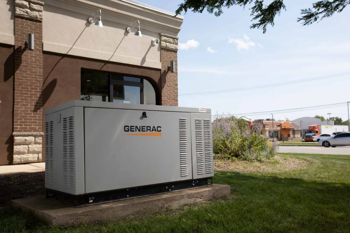 A Generac commercial standby generator on a concrete pad beside a business