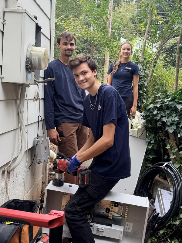 The three Hill kids on an install, one using a drill at the transfer switch